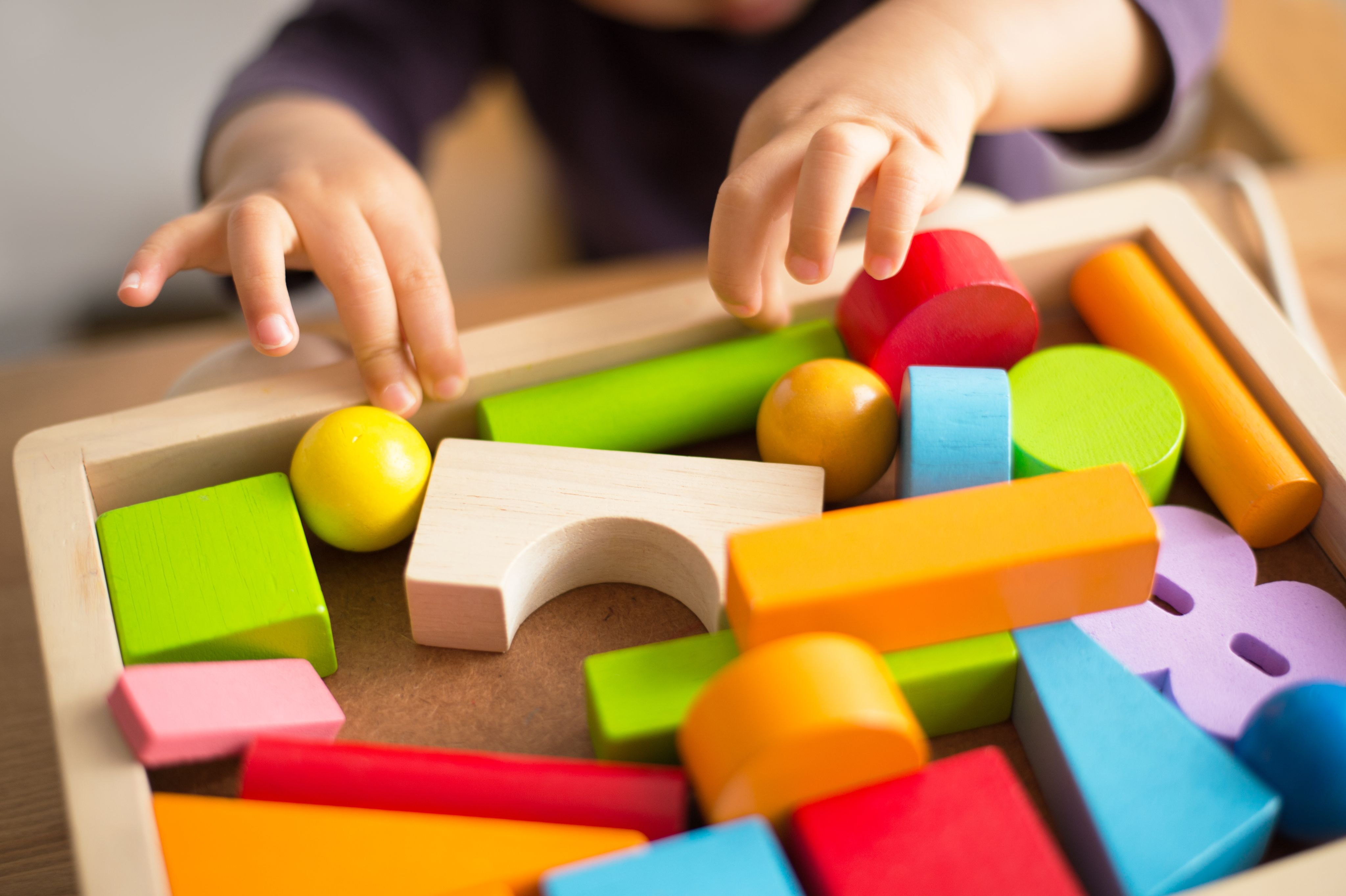 Image of a child's hands playing with wooden toy pieces