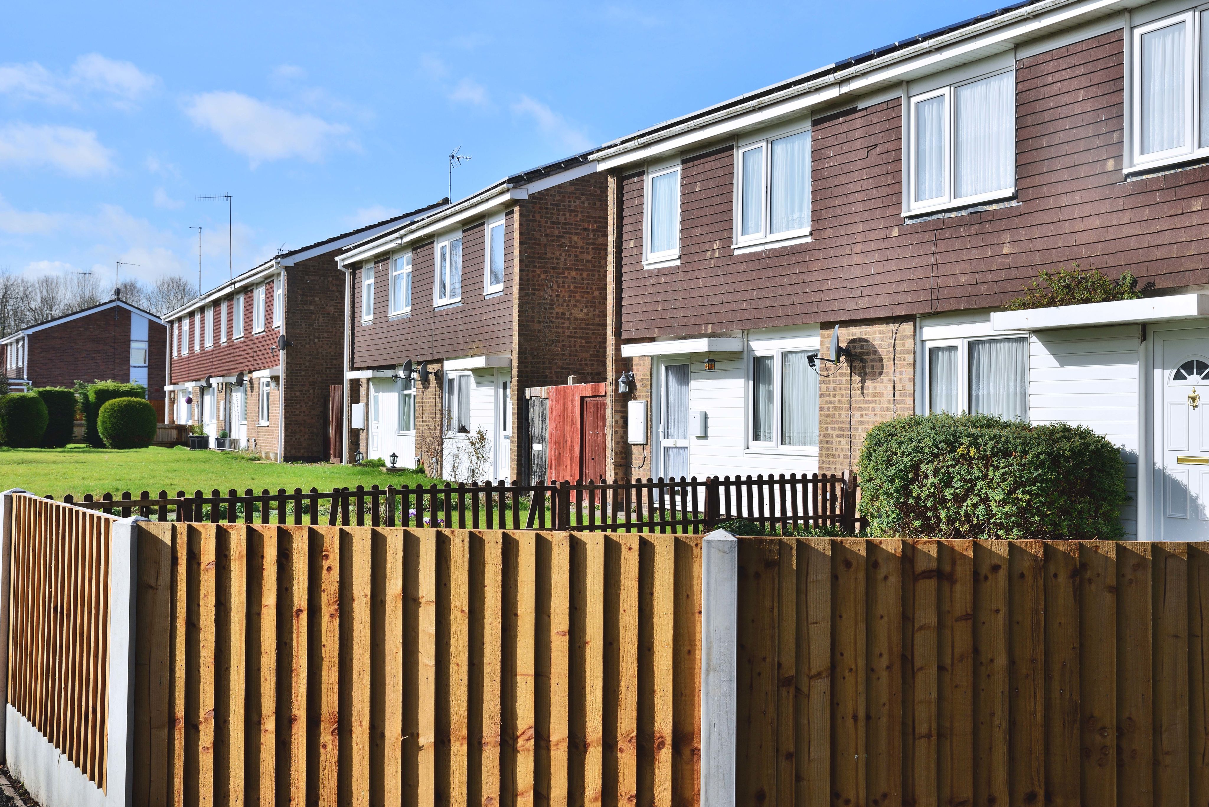 A row of houses fronted by a lawn and fencing