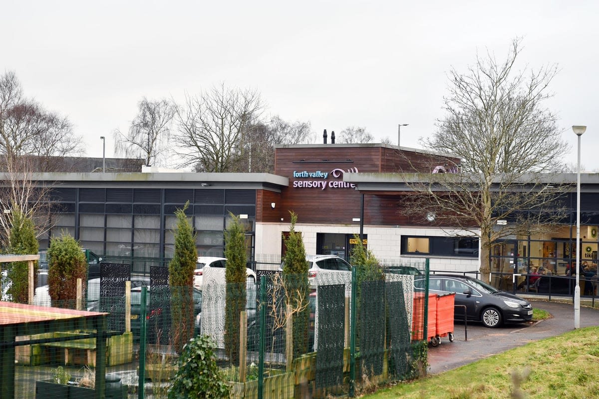 The Forth Valley sensory centre building from outside. It is a low, modern, wooden-clad building with greenery in the foreground and cars parked outside.