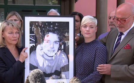 Image of Owen's parents and sister holding up a framed photo of him.