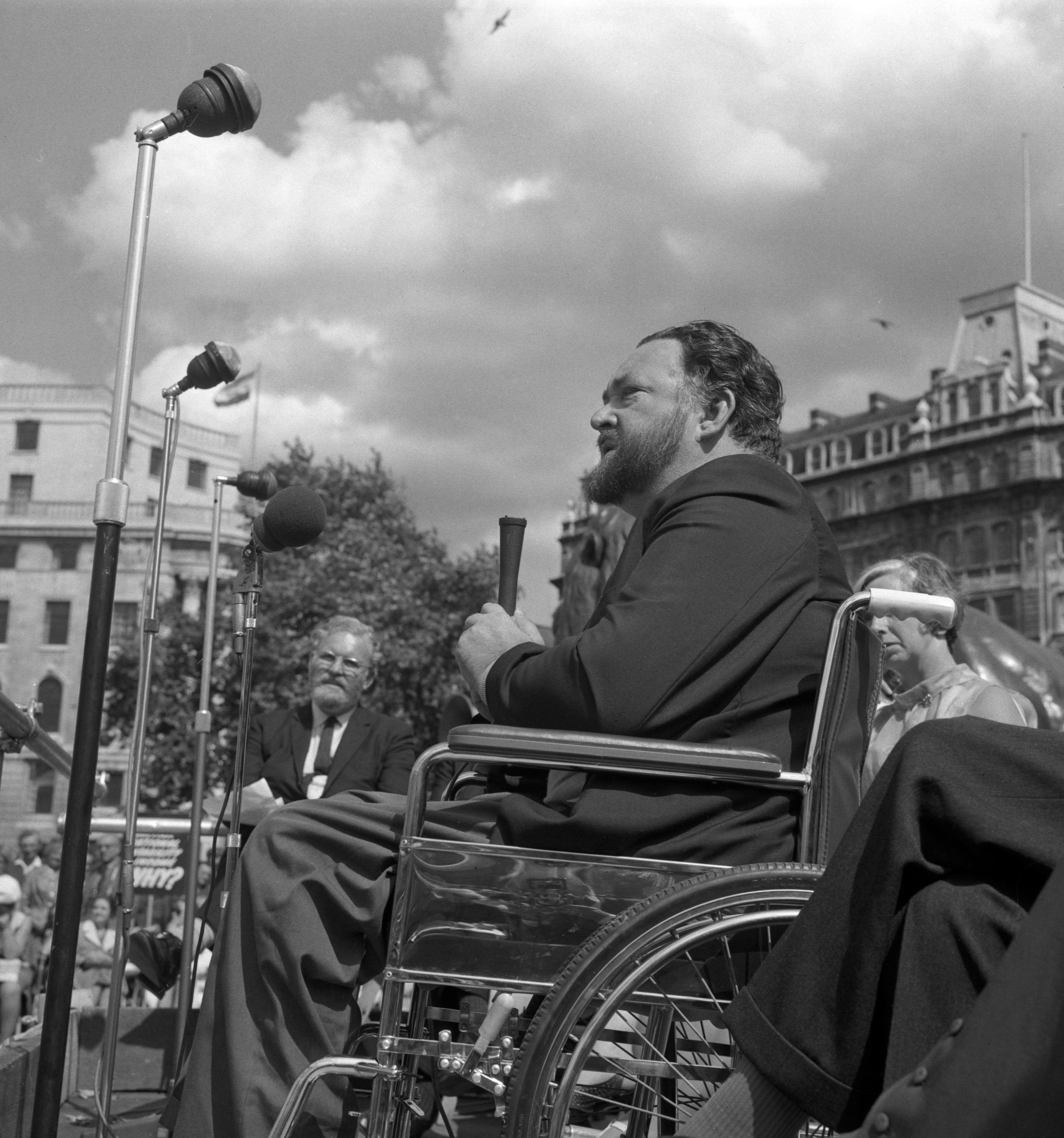 Image of Michael Flanders, of Flanders and Swann entertainers fame, addressing a Disablement Income Group's rally in Trafalgar Square, London. Mr Flanders is himself confined to a wheelchair due to polio contracted during World War Two.
